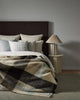 A cosy looking bed with a neutral toned check throw blanket in a wool blend. 