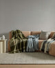 A modern style couch with green and blue throw blankets from Weave Home's Autumn Winter 2025 collection draped across it. 