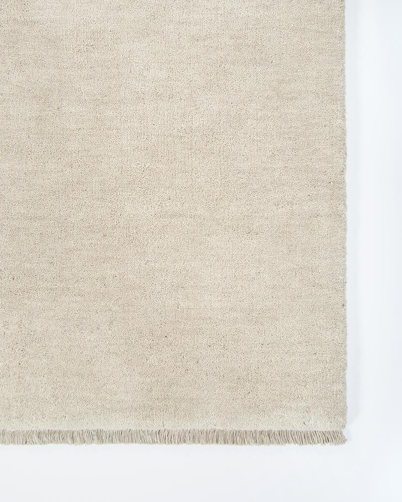 The Sandringham 'Merino' creamy white floor rug, close up showing the fringe detail and soft colour.