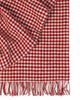 A folded throw blanket with a houndstooth pattern in red and white and with a twisted fringe edge. 