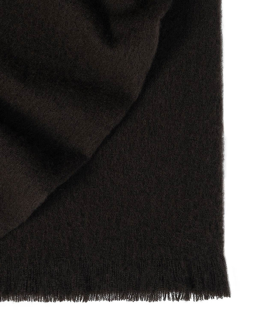 A folded wool blend throw blanket in a dark rich chocolate brown with fringed edging. 