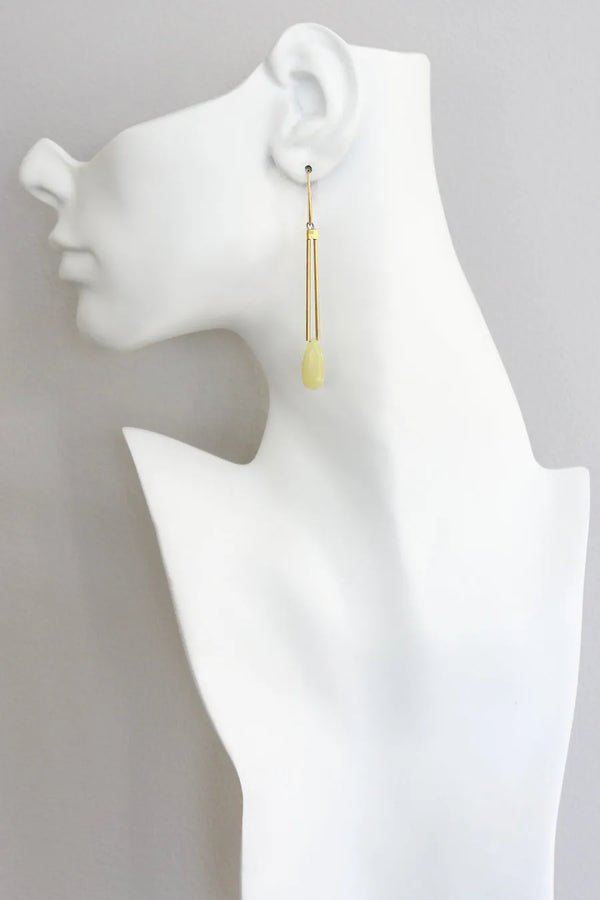 Elegant yellow jade dangle earrings with brass tubes and gold plated hooks, by David Aubrey, seen on a model