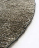 Detail view of edge of a round, earth-toned rug by Baya NZ