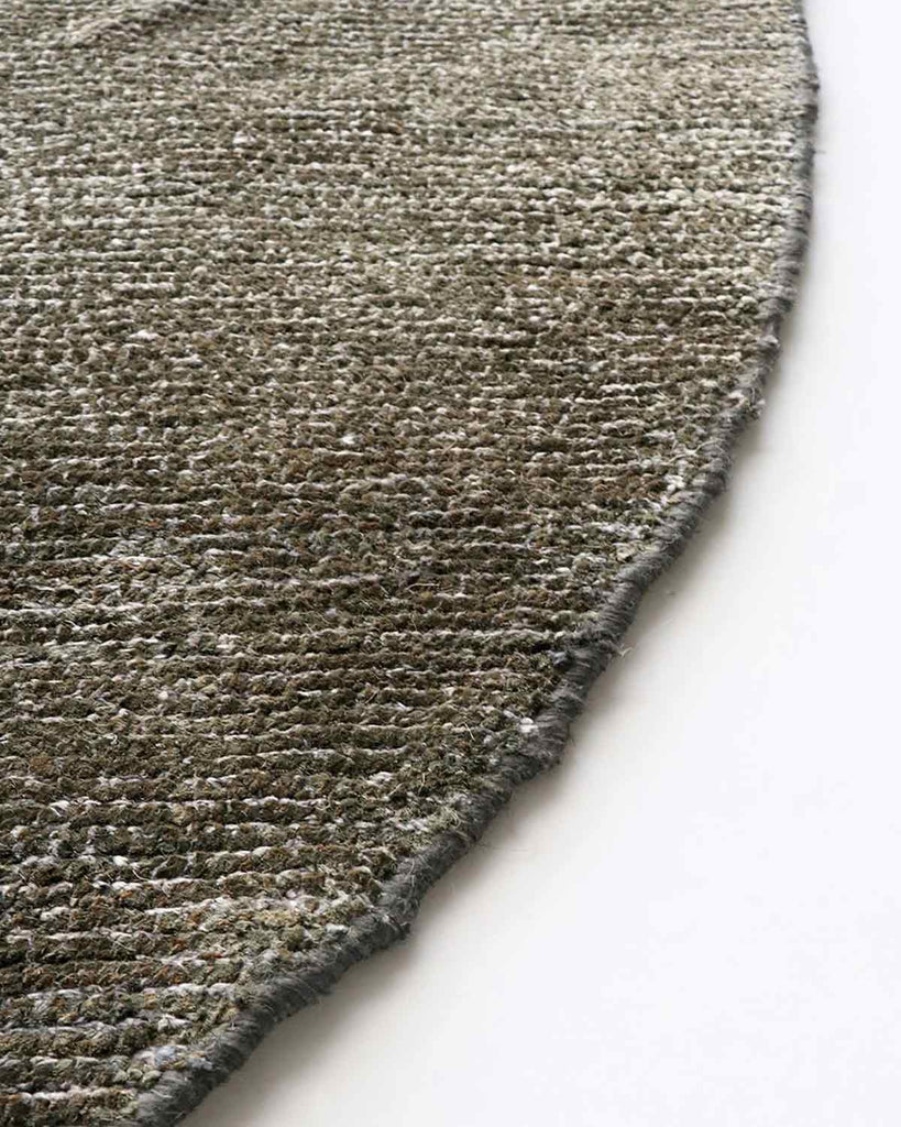 Detail view of edge of a round, earth-toned rug by Baya NZ