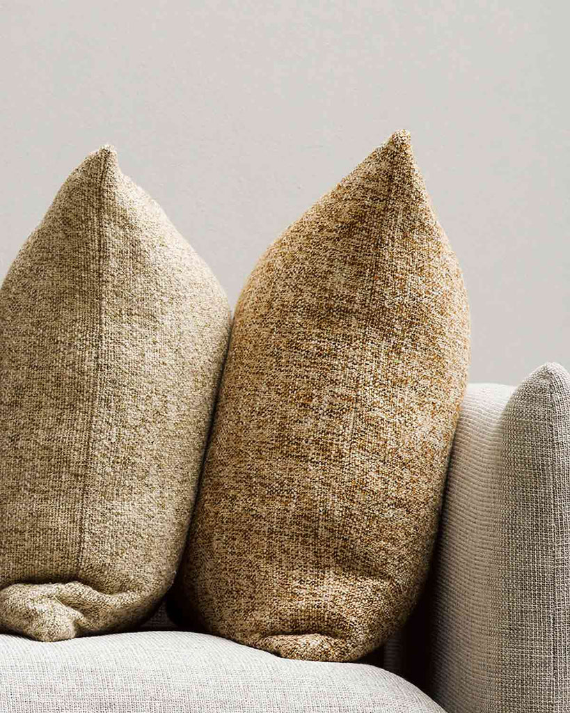 Two of the Cumbria cushions by Baya on a couch, their textural weave and complimentary yellow and cream tones adding sophistication and interest to the room. 