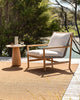 A brown, basketweave outdoor rug by Baya NZ, sitting on a sunny deck with a chair and table. 