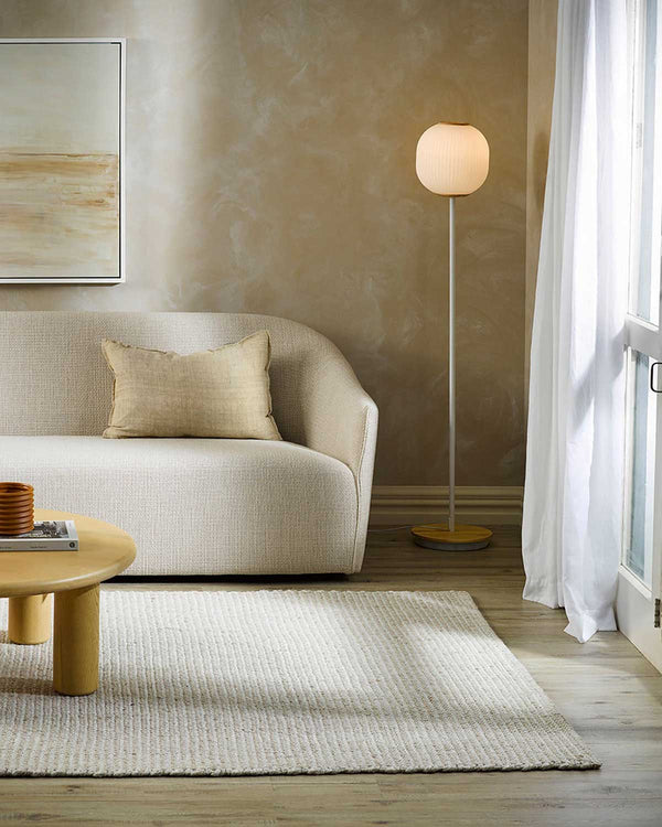 A warm beige rug by Baya NZ, situated in a stylish, neutral toned modern living room. 