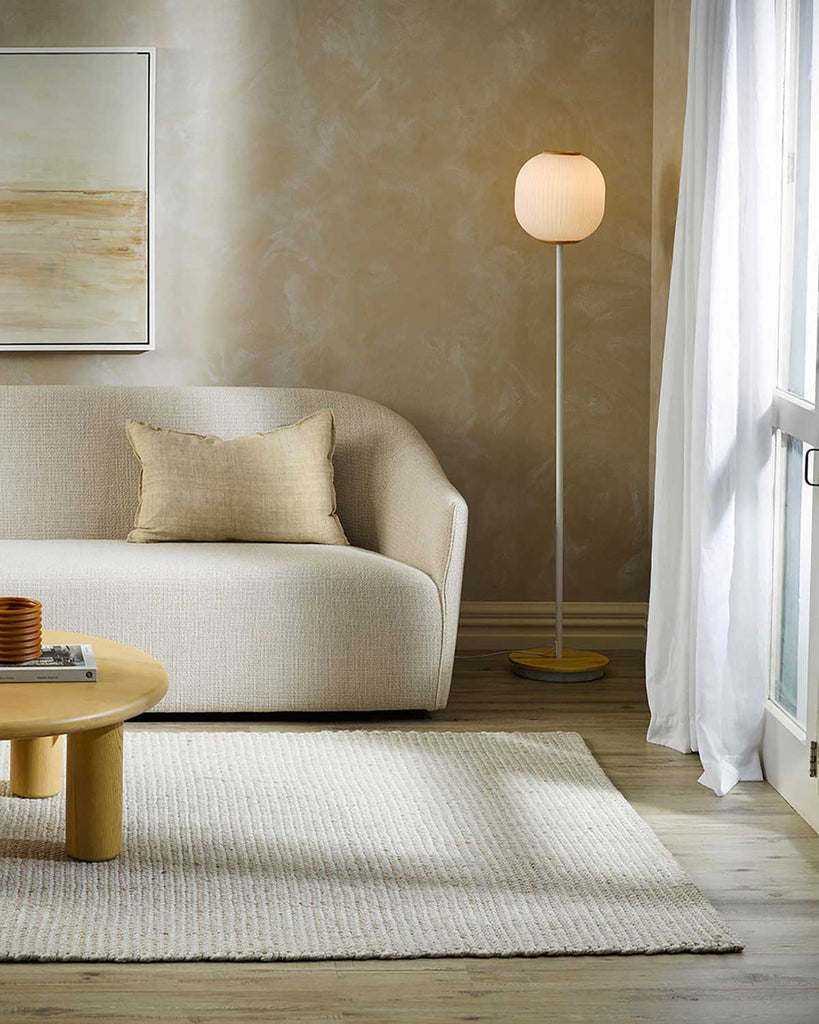 A warm beige rug by Baya NZ, situated in a stylish, neutral toned modern living room. 