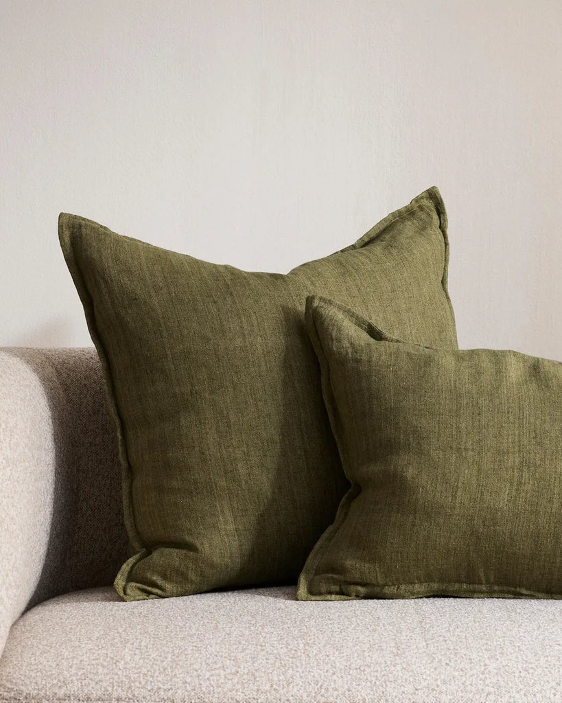 Close up of the Baya Cassia and Arcadia linen cushions in miltary green, shown on a contemporary couch