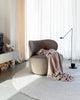 The Baya 'Cromwell Blush' throw blanket draped on a chair in a contemporary living room