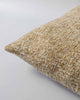 Corner view of a textural woven cushion in shades of muted mustard yellow and ercu, by Baya