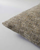 Corner view of a  textured woven cushion in shades of pebble brown and ercu, by Baya