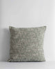 A textural cushion in shades of sage green and ercu, with a prominent weave, by Baya. 