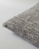 Corner view of a textural woven cushion in shades of slate, blue-black and ercu, by Baya