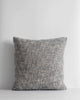A textural woven cushion in shades of slate, blue-black and ercu, by Baya