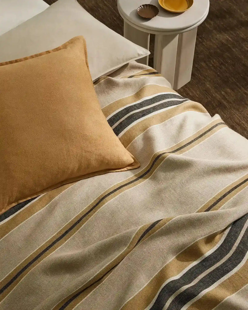 A honey coloured lumbar cushion decorating a bed in a stylish room