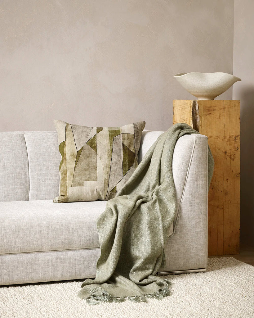 The Baya 'Grove Olive' abstract patterned cushion on a couch with the Richmond sage throw, in a stylish living room