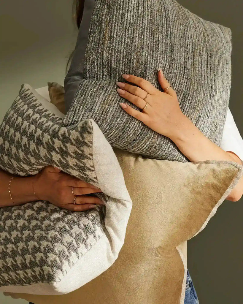 Weave Home cushions including the 'Vista Mineral', a textural weave in rock-inspired greys and browns, held by a woman