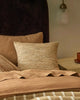 Th 'Vista Sunset' cushion featuring a texturla weave in warm brown colours, by Weave Home nz, on a bed in a modern bedroom