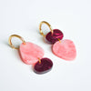 A pair of acrylic earrings in organic shapes with charms in coral pink and merlot shades. 