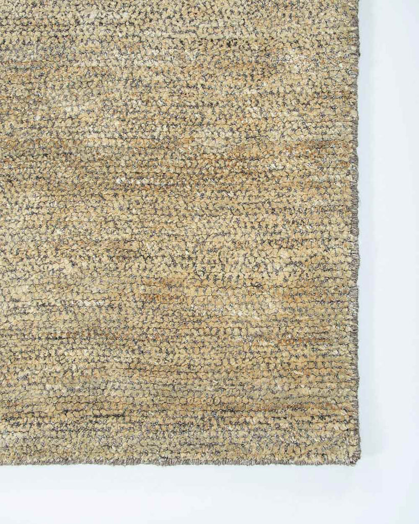 A corner image of the Baya Fairbanks floor rug in Limestone, a soft beige. The weave of the rug catches the light beautifully. 
