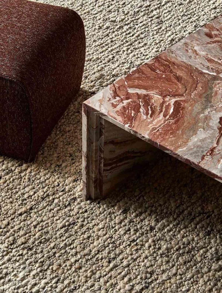 A textural wool blend boucle style rug by Globe West and Soren Liv NZ in shades of light grey and brown, situated in a stylish living room. 