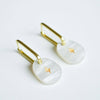 A pair of earrings with stylish square gold hoops and a pearl coloured iridescent acrylic charm with a sweet gold star etched into it. 