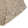 Close up of the weave of a textural wool blend boucle style rug by Globe West and Soren Liv NZ in shades of light grey and brown. The edge of the rug is flipped, revealing the underside. 