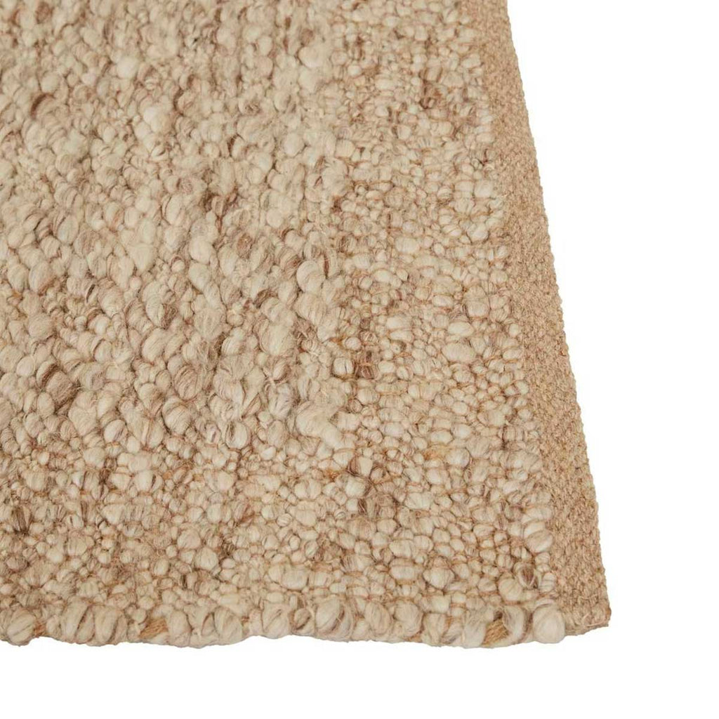 Close up of the corner of a textural wool blend boucle style rug by Globe West and Soren Liv NZ in shades of warm beige and light brown, with indented edges