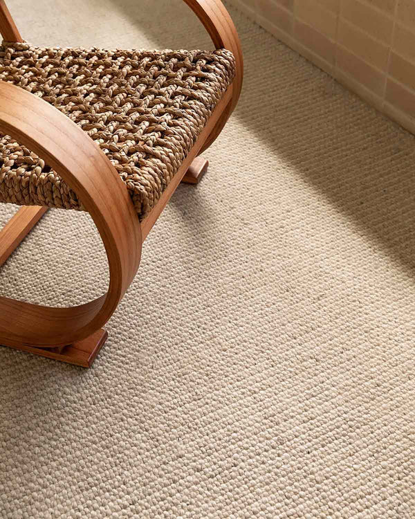 A close up of a chair on top of a woven warm toned rug by Baya NZ