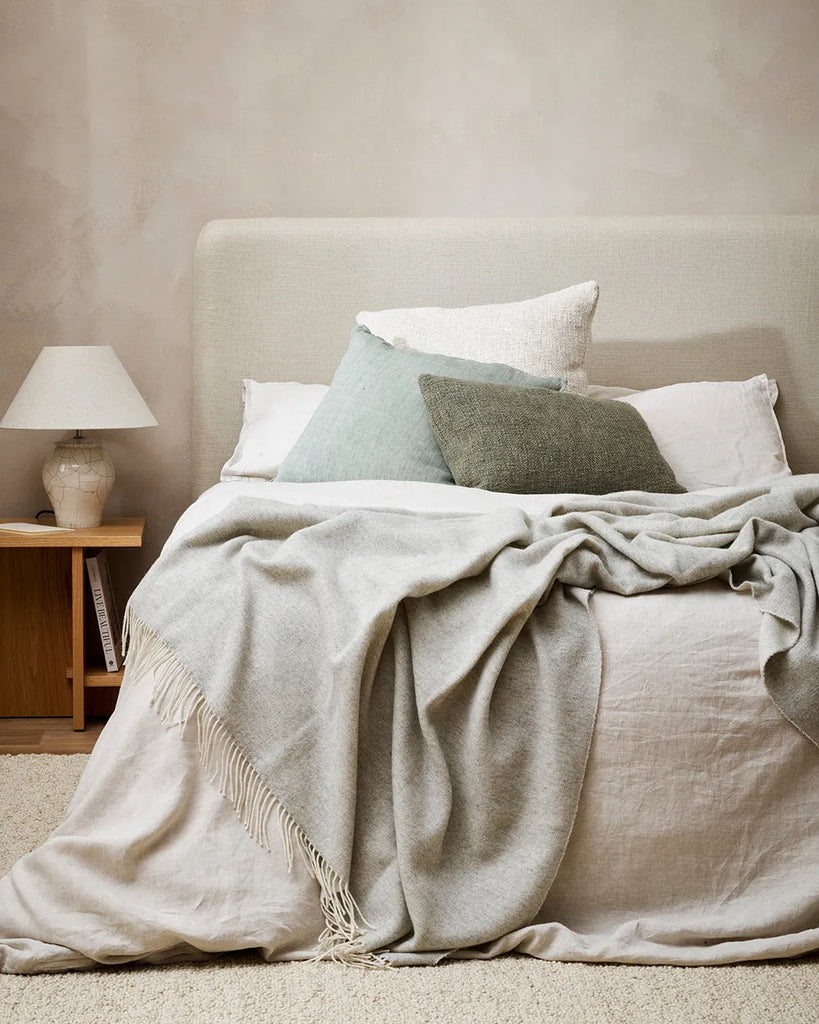 Large, silver grey merino throw blanket seen draped at the end of a bed