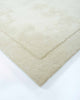 The corner of the Norfolk floor rug in Ivory. The minimalist cut-pile of the edges adds interest to this luxurious, 100% wool piece. 