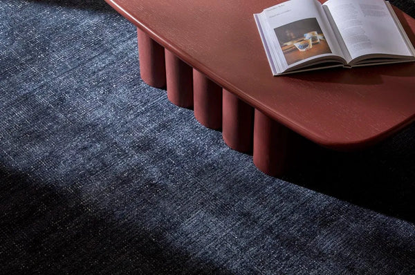 A deep blue wool blend foor rug seen under a modern coffee tabel