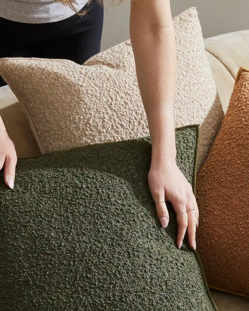 A lady placing boucle cushions by Weave nz on a modern couch