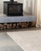 The Baya woven textural floor rug 'Omaha' in colour 'Pebble' on a concrete floor