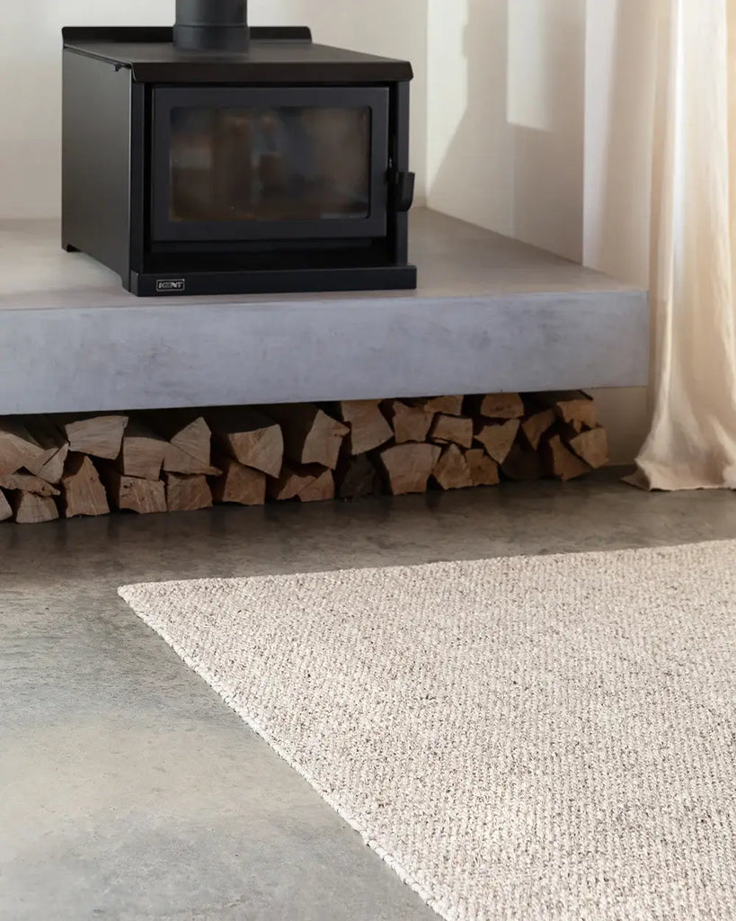 The Baya woven textural floor rug 'Omaha' in colour 'Pebble' on a concrete floor