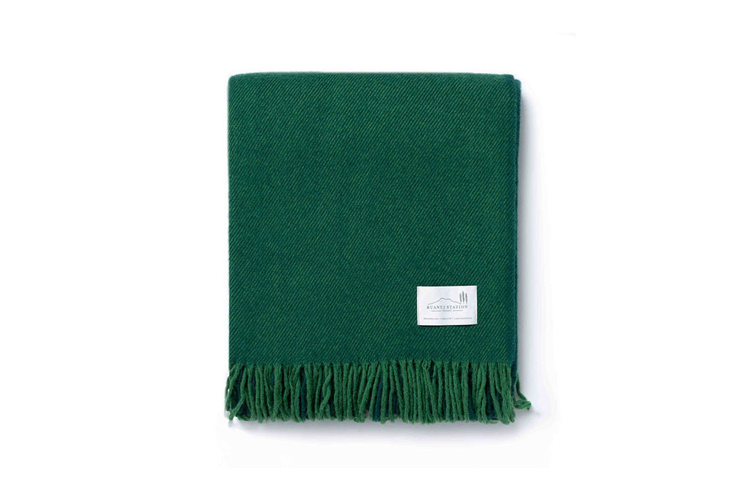 A folded green throw blanket by Ruanui Station NZ.