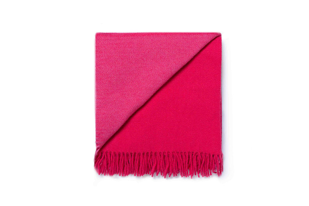 A folded bright pink throw blanket by Ruanui Station NZ, folded back on itself to show the differentiation in tones of the wool. 