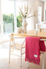 A modern dining room, with a pink throw blanket by Ruanui Station NZ folded over the side of one of the chairs. 