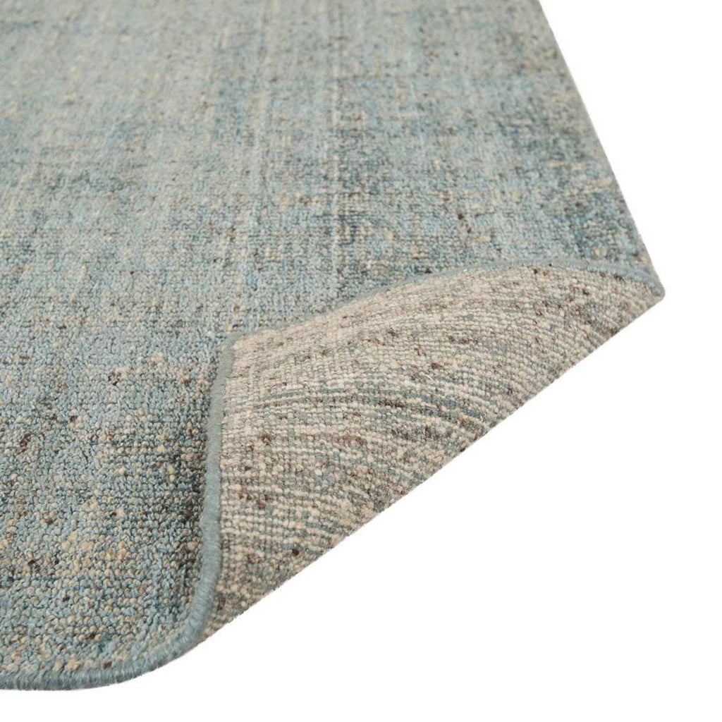 Close up of the weave of a viscose blend statement rug in shades of muted ocean blue, by Globe West and Soren Liv NZ. The edge is flipped up to show the underside of the rug. 