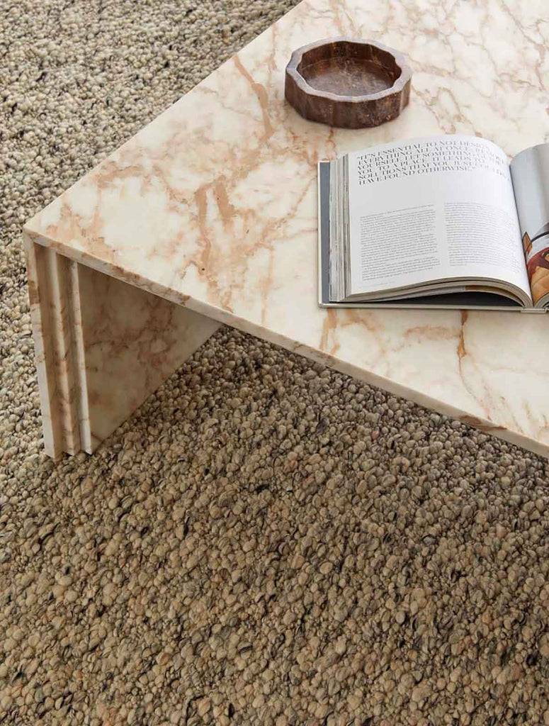 A textural wool blend boucle style rug by Globe West and Soren Liv NZ in shades of light grey and brown, situated in a stylish living room. 