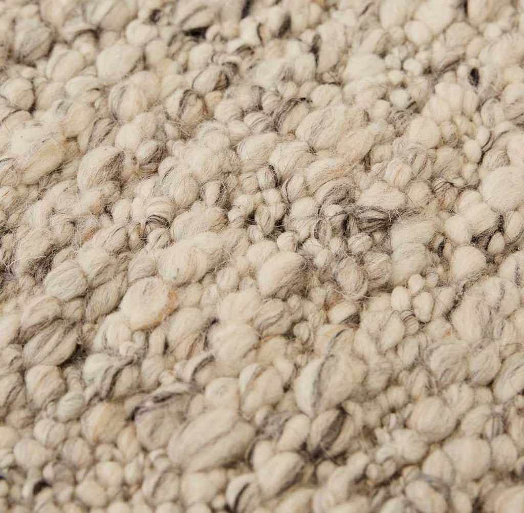 Close up of the weave of a textural wool blend boucle style rug by Globe West and Soren Liv NZ in shades of light grey and brown.