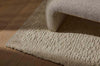 A textural wool blend boucle style rug by Globe West and Soren Liv NZ in shades of warm ivory and cream, situated underneath a designer couch. 