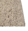 Close up of the corner of a textural wool blend boucle style rug by Globe West and Soren Liv NZ in shades of light grey and brown. The edge of the rug is indented, showing interest to the rug 