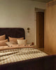 Designer cushions in warm brown tones, in a contemporary berdroom setting