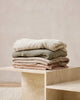 Pile of Baya cotton-blend throw blankets in muted trending colours