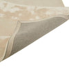 Detailed view showing the corner of a cream, light natural beige floor rug with geometric designs rendered in alternating pile heights, by Globe West and Soren Liv NZ. The edge of the rug is flipped up to reveal the underside. 