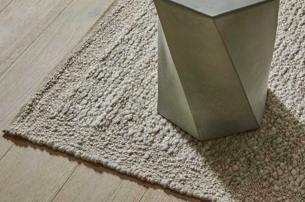 A textural wool blend boucle style rug by Globe West and Soren Liv NZ in shades of warm beige and light brown, situated under a coffee table.