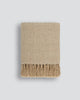 Light brown throw blanket with tasseled fringe, the Baya 'Richmond Putty' seen folded