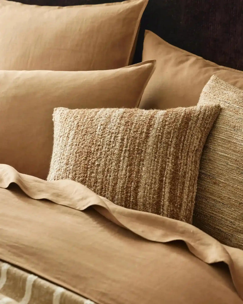 A brown textural weave cushion on a bed